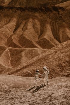 Two astronauts holding hands in surreal Martian-like landscape, shadows cast on barren terrain.