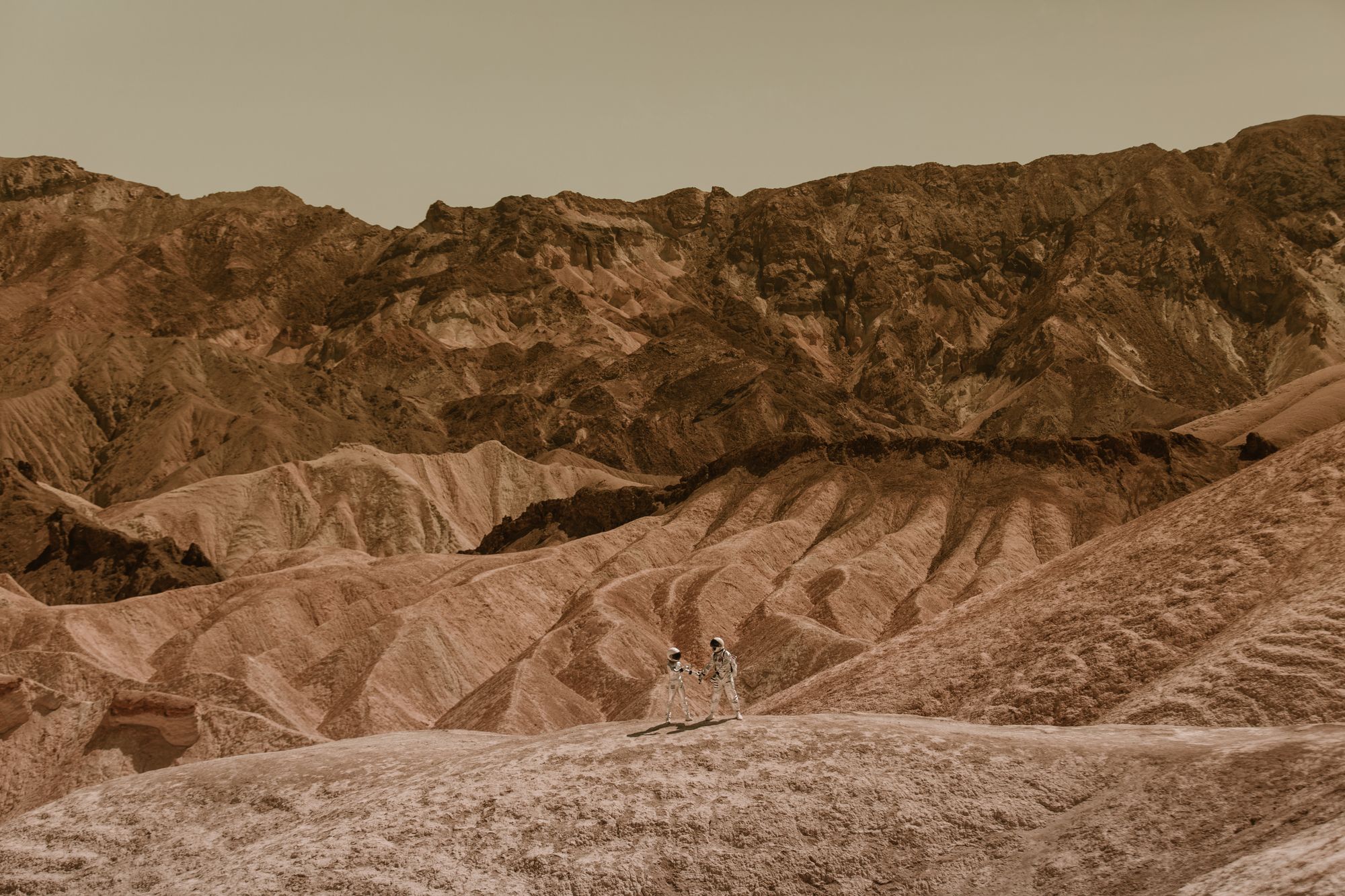 Two astronauts walking on a desolate, rocky landscape resembling Mars.