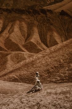 A lone astronaut stands on a barren rocky desert, evoking exploration and solitude.
