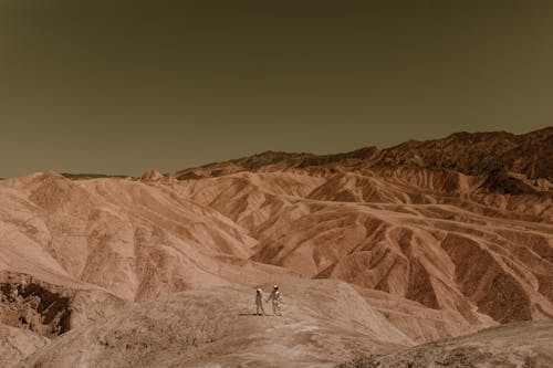 2 People Walking on Brown Mountain