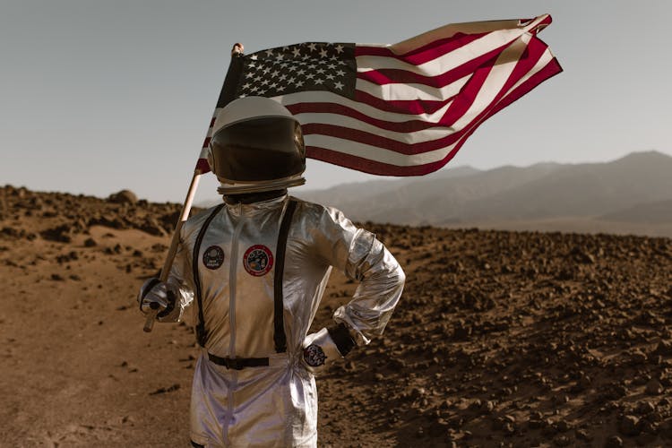 A Person In Space Suit Carrying The American Flag