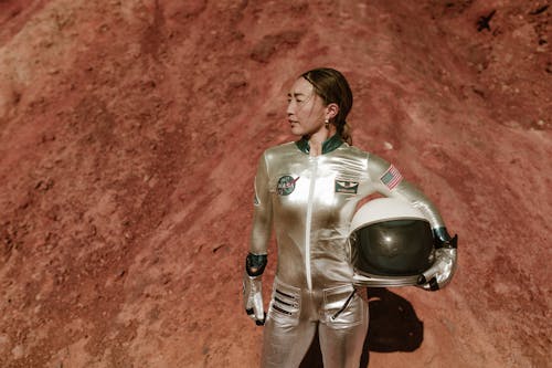 A Woman in Space Suit Carrying Her Helmet