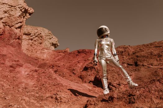 Astronaut in space suit standing on red rocky terrain resembling Mars' surface.