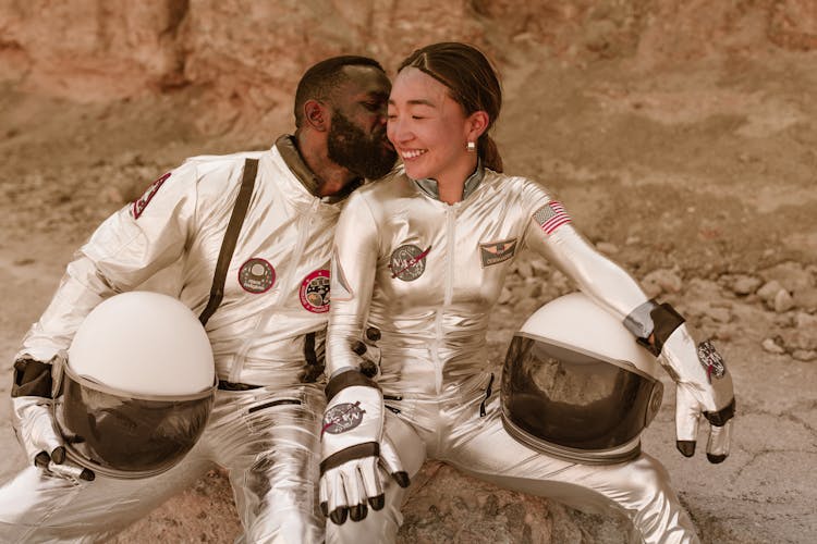 Man And Woman In Astronaut Costumes Kissing Cheeks 