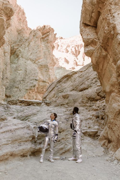 Free Two people in astronaut suits explore a rocky canyon, evoking a sci-fi setting. Stock Photo