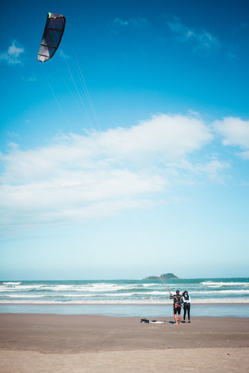 Free Person Standing on Beach Preparing for Kitesurfing Beside Another Person Stock Photo
