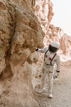 An astronaut in a space suit examining rock formations on a desert-like terrain, evoking sci-fi exploration.