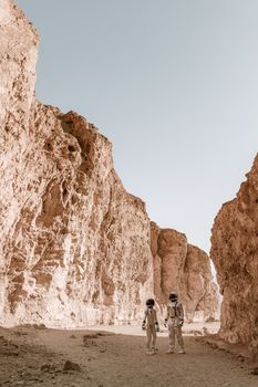 Astronauts exploring a barren, rocky terrain that resembles a Martian landscape.