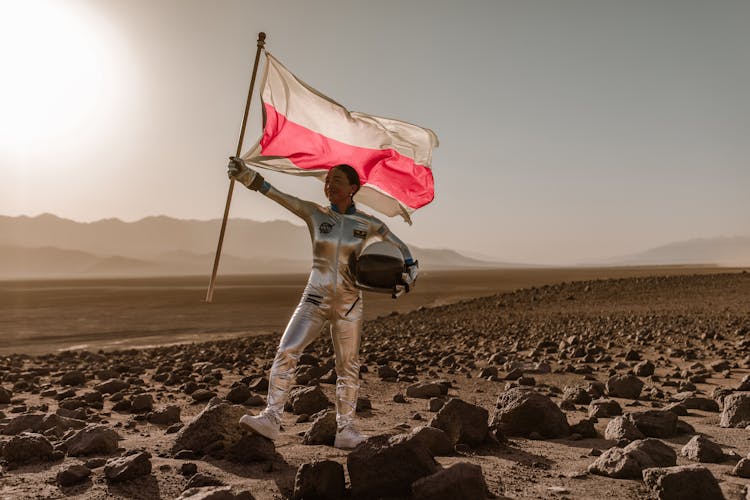 A Female Astronaut Holding The Flag Of Belarus In A Barren Landscape