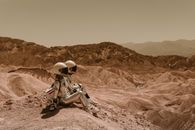 Man in White Shirt and Brown Pants Sitting on Brown Rock Mountain