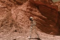 Man in White and Black Suit Standing on Brown Rock Formation
