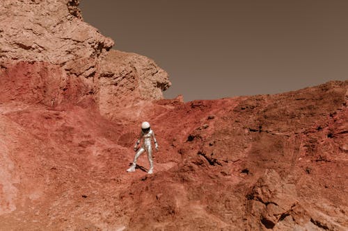 Person in Silver Spacesuit Standing on Sandstone
