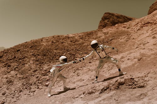 Astronauts Helping Each Other to Climb a Mountain