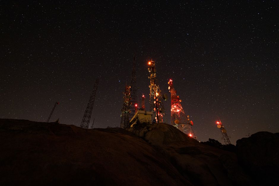 A mesmerizing night view of illuminated communication towers under a starry sky. A mesmerizing night view of illuminated communication towers under a starry sky.