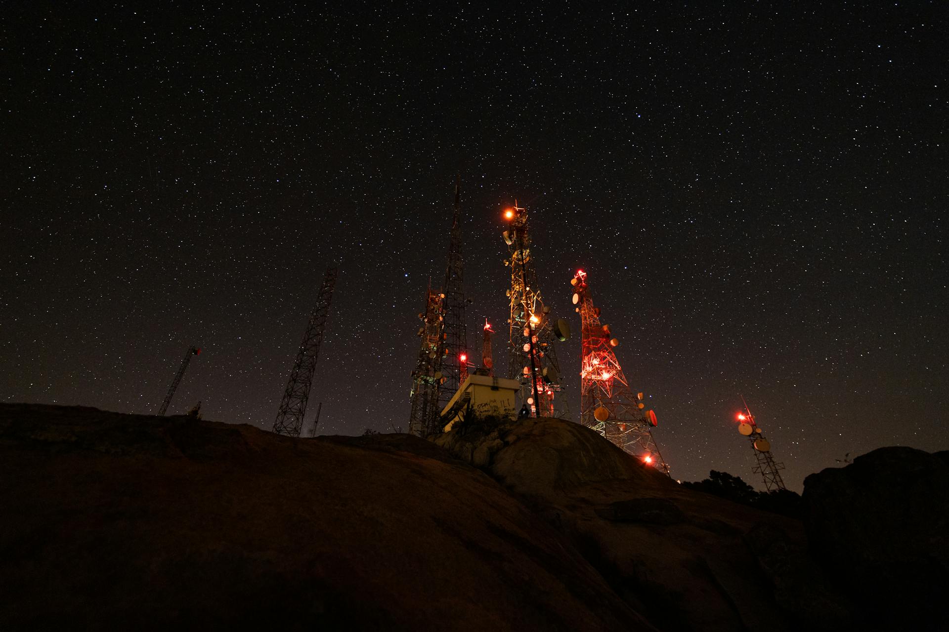 A mesmerizing night view of illuminated communication towers under a starry sky.