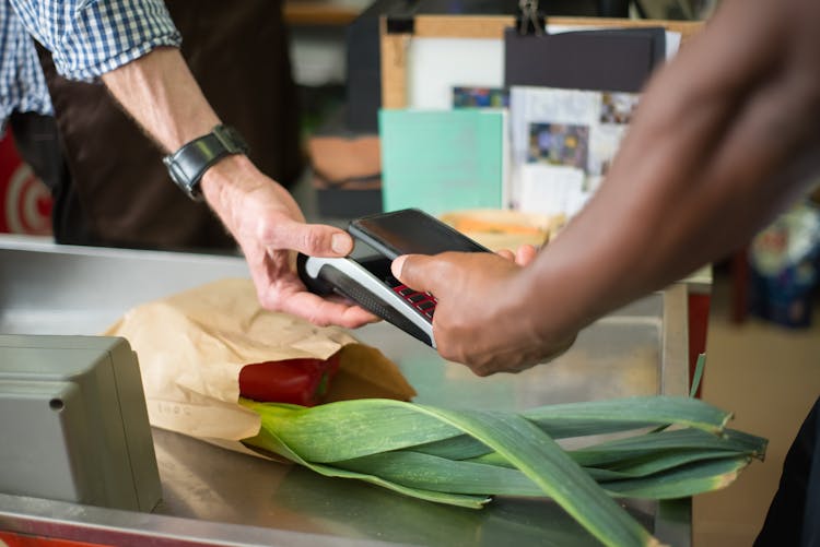 A Customer Paying For Groceries Using A Smartphone