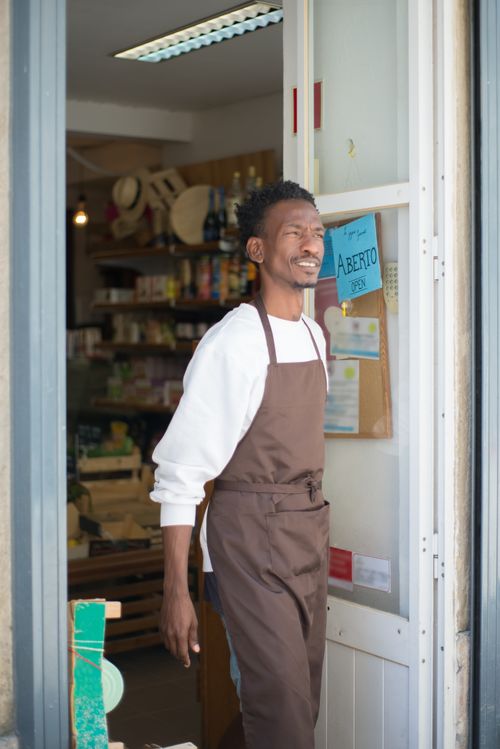 Free A smiling shopkeeper stands in the doorway, inviting customers into the store. Stock Photo