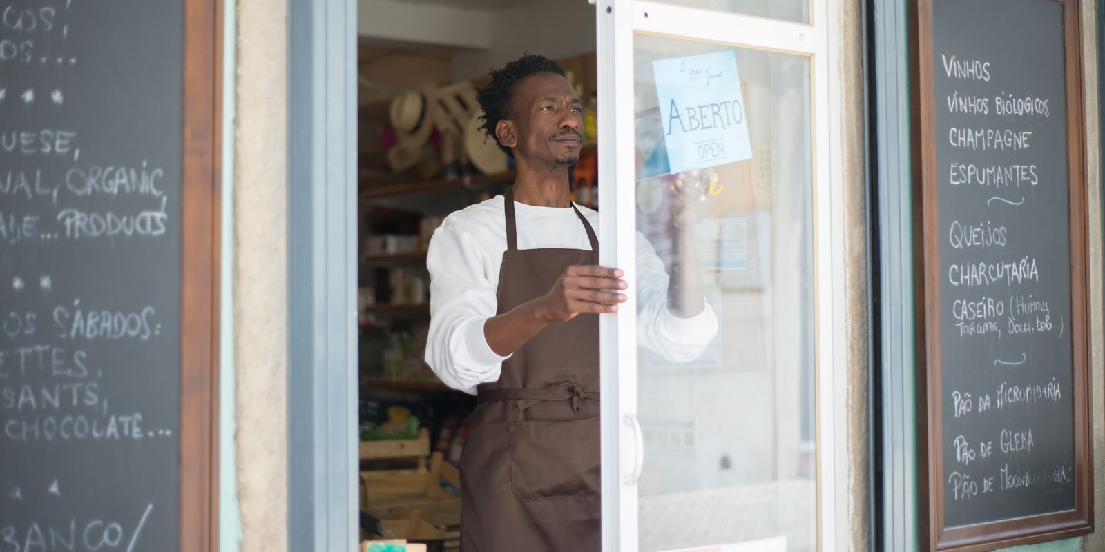 A small business owner flipping an "open" sign on a shop door