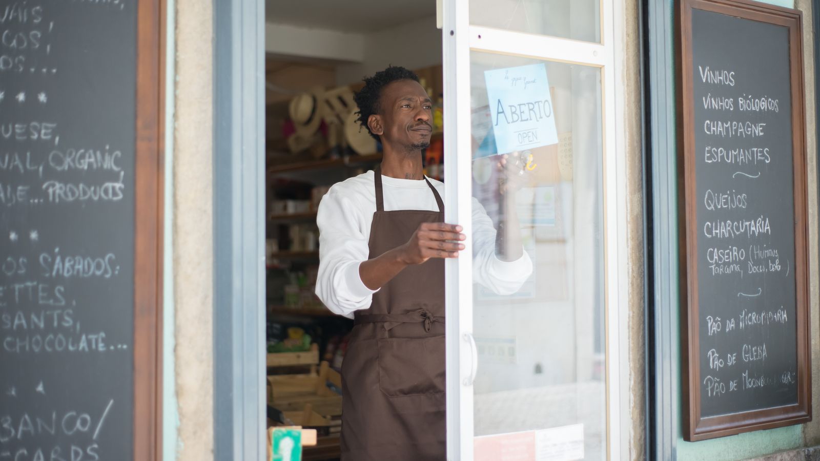 A small business owner flipping an "open" sign on a shop door