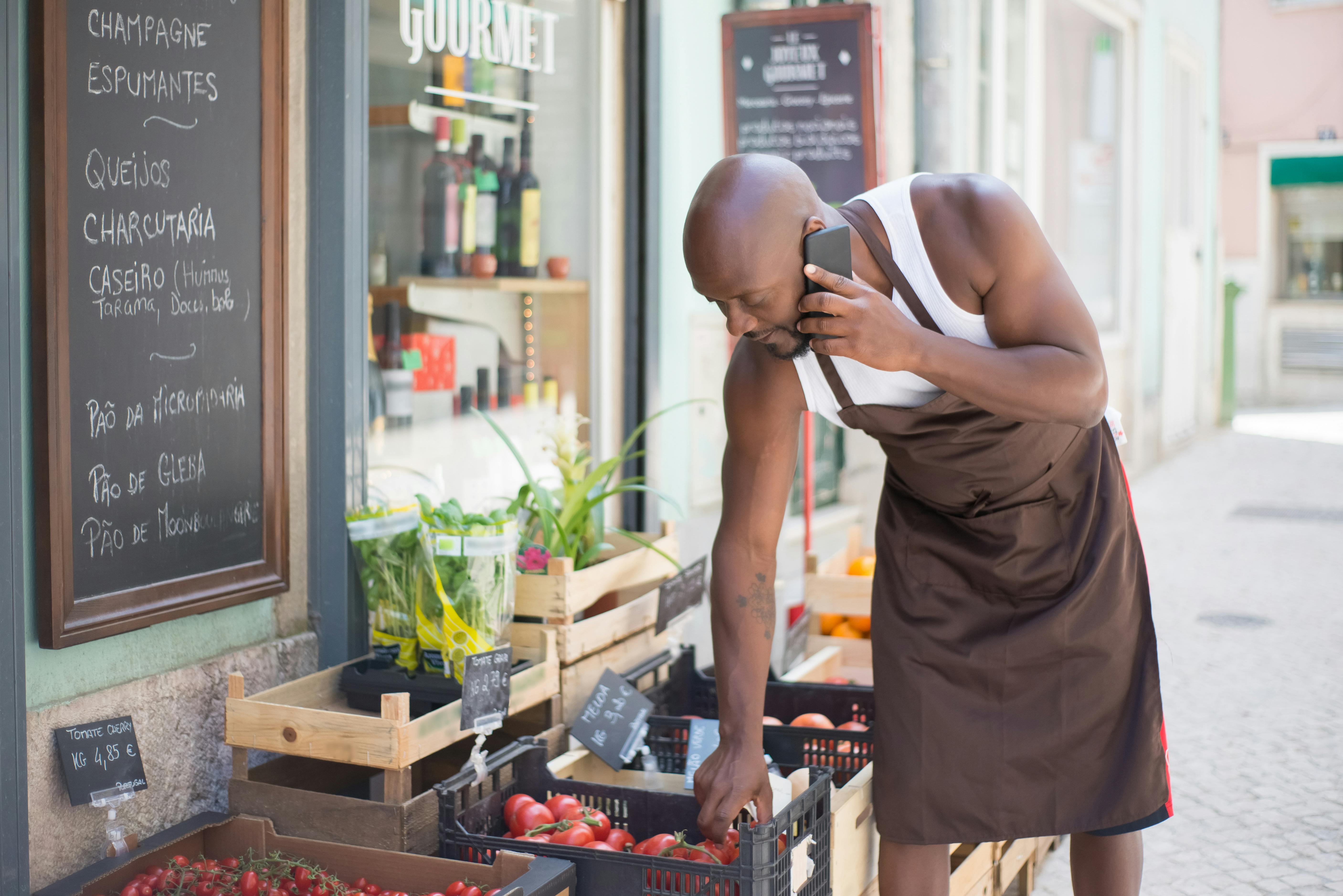 Street vendor talks on phone while selling fresh produce at a Portuguese market.