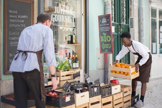 Two vendors organizing organic fruits and vegetables at a street market in Portugal.
