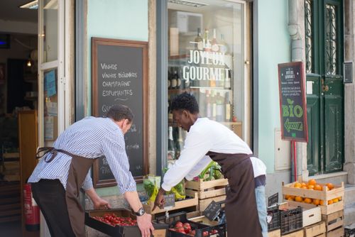 Free Two men organizing produce outside a gourmet store in Portugal on a sunny day. Stock Photo