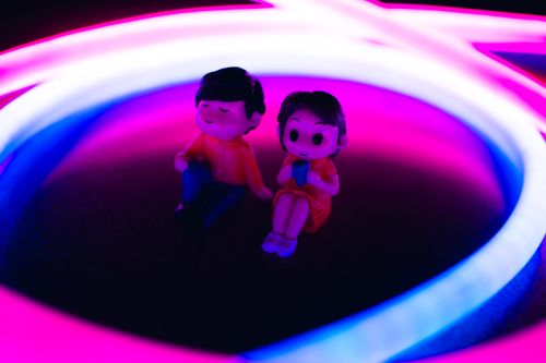 Free Cute figurines illuminated by vibrant neon lights in a playful scene. Stock Photo