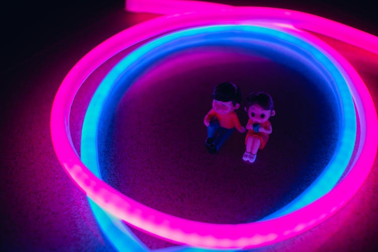 Man And Woman Figures In The Middle Of Neon Lights