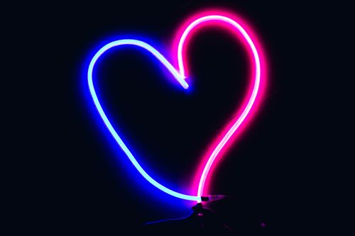 Free Vibrant neon heart light in pink and blue, perfect for Valentine's Day themes. Stock Photo