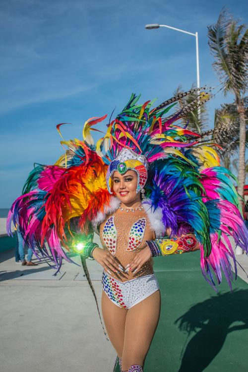 Free Smiling woman in vibrant feathered costume at outdoor festival. Stock Photo