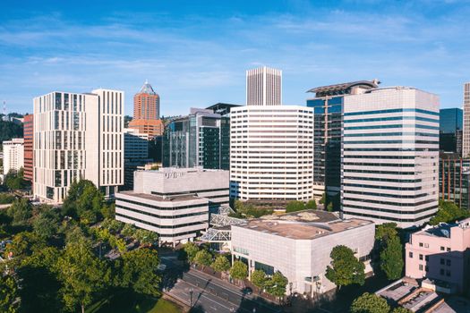 Aerial view of a modern skyline with high-rise buildings and lush greenery on a sunny day.