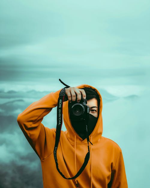 Free A Man in Yellow Hoodie Taking Picture Using a DSLR Camera Stock Photo