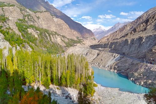 Free Beautiful landscape of a turquoise river winding through a lush green valley surrounded by mountains. Stock Photo