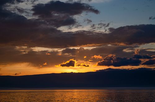 Free A breathtaking sunset over the ocean with vibrant colors and dramatic clouds. Stock Photo