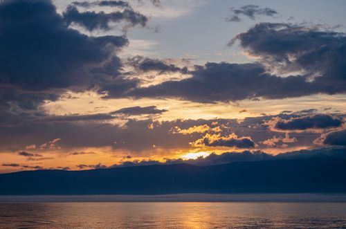 Free Stunning view of a dramatic sunset with dark clouds over a calm sea, capturing the beauty of nature. Stock Photo