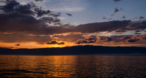Free Serene ocean sunset with vibrant colors and dramatic clouds over the horizon. Stock Photo
