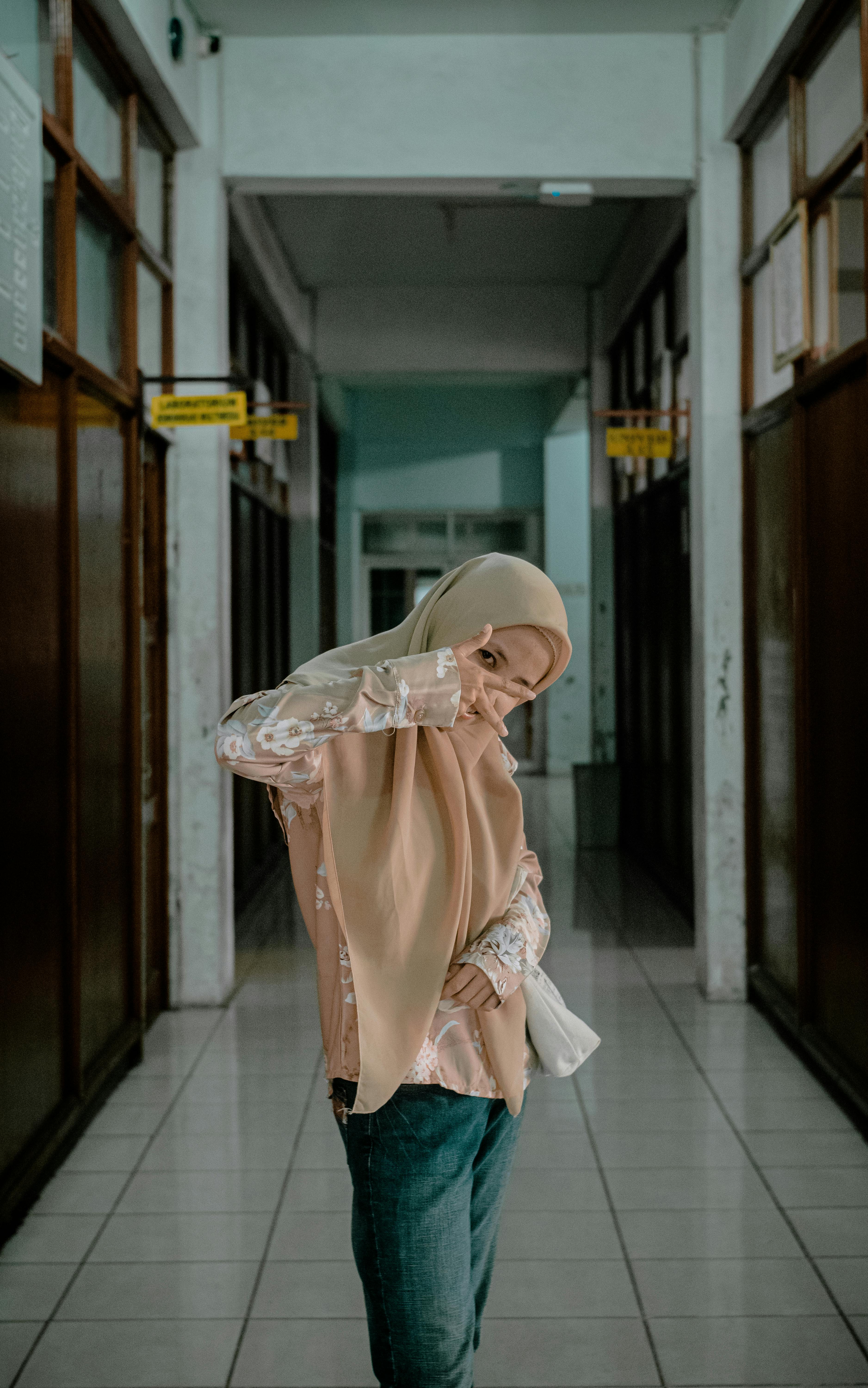 A woman in a hijab poses indoors, showcasing confidence in a hallway.