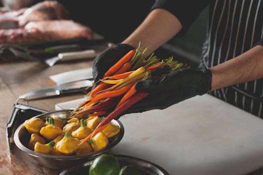 Chef wearing gloves handles fresh carrots and patty pan squash, highlighting preparation