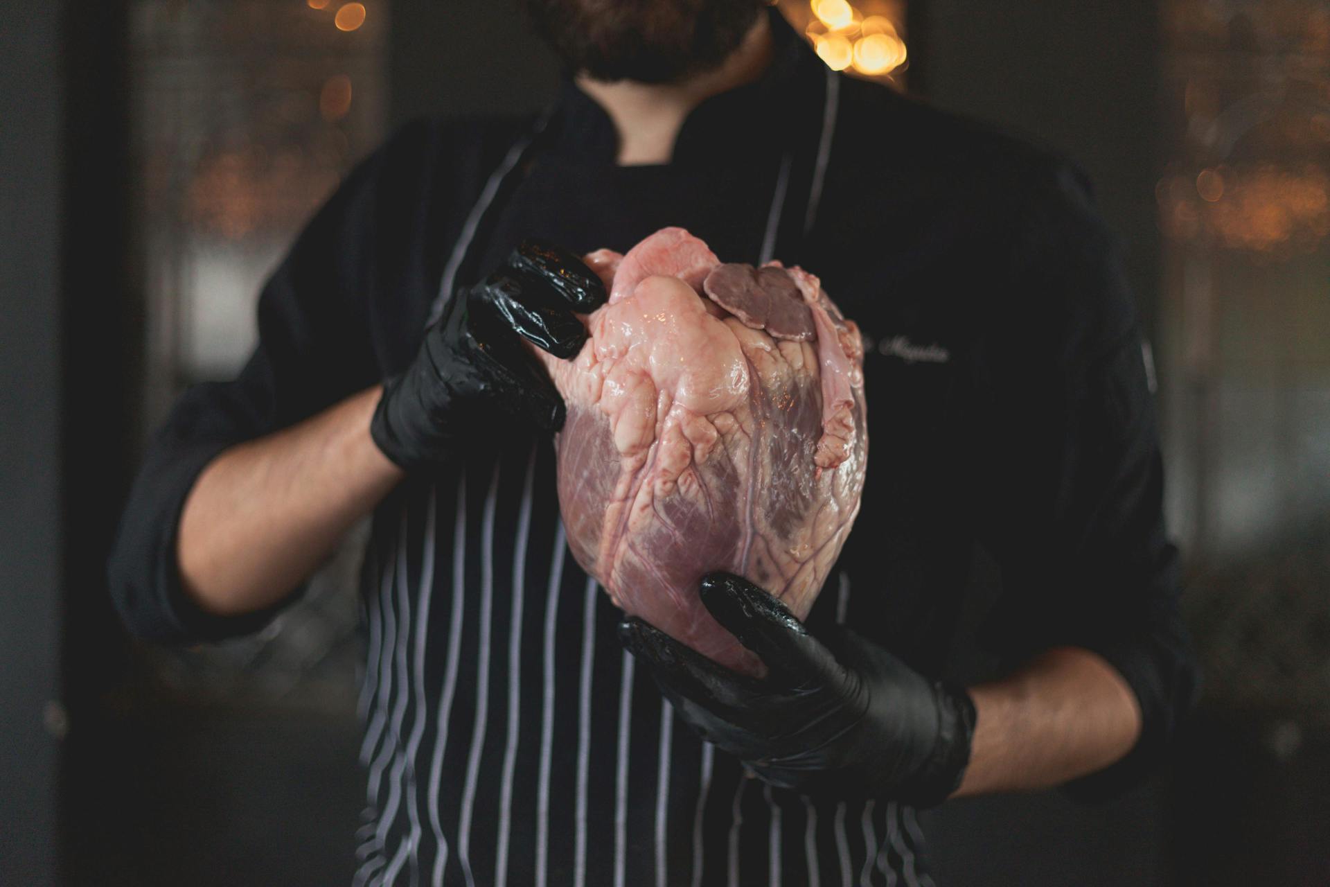 Man Wearing a Stripe Apron Holding a Raw Meat