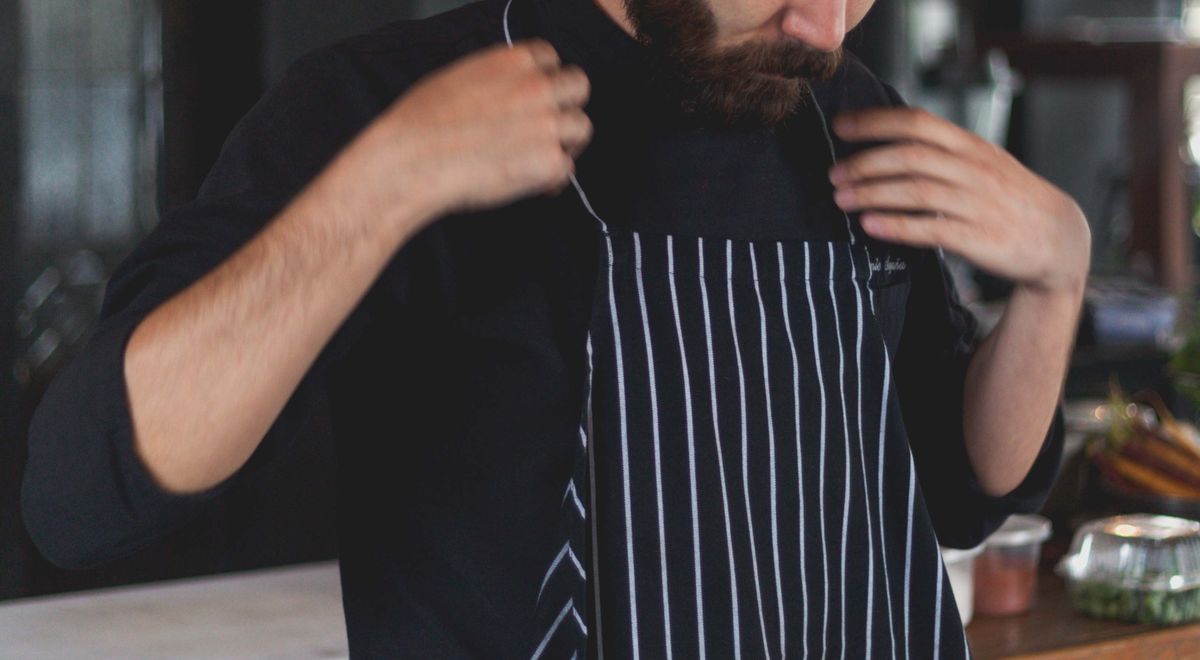 Chef enfilant un tablier à bavette avant de cuisiner en cuisine professionnelle