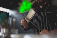 Man Wearing an Apron Sharpening a Knife