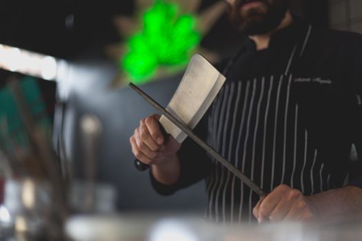 Man Wearing an Apron Sharpening a Knife