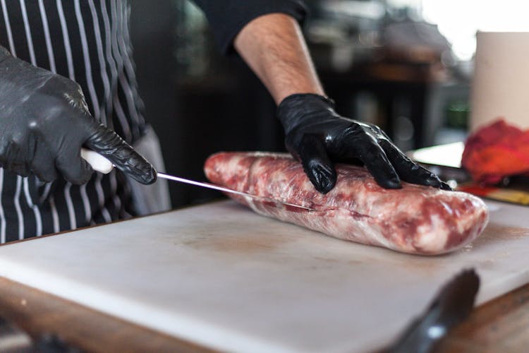 Person Slicing A Raw Meat