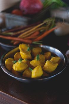 Fresh patty pan squash in a rustic kitchen with carrots and onions in the background.