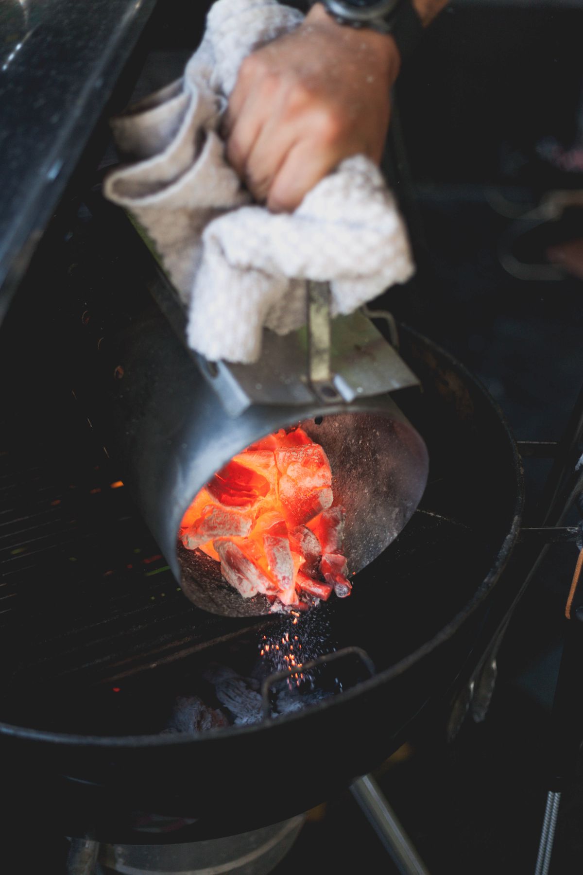 Glowing charcoal being poured from a chimney starter