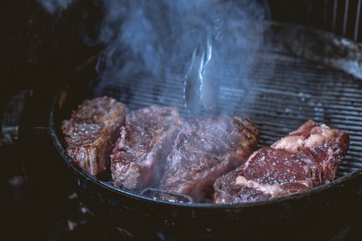 Close-up of juicy steaks sizzling on a smoky barbecue grill, ideal for a food or lifestyle theme.
