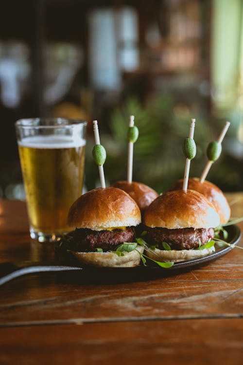 Free Cheese Burgers on a Plate Beside a Glass of Beer Stock Photo