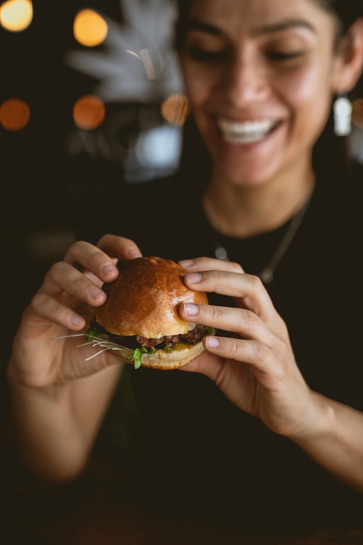 A Smiling Woman Holding A Burger