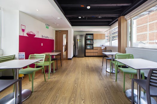 Bright and minimalist office kitchen with tables and chairs, promoting a healthy lifestyle.