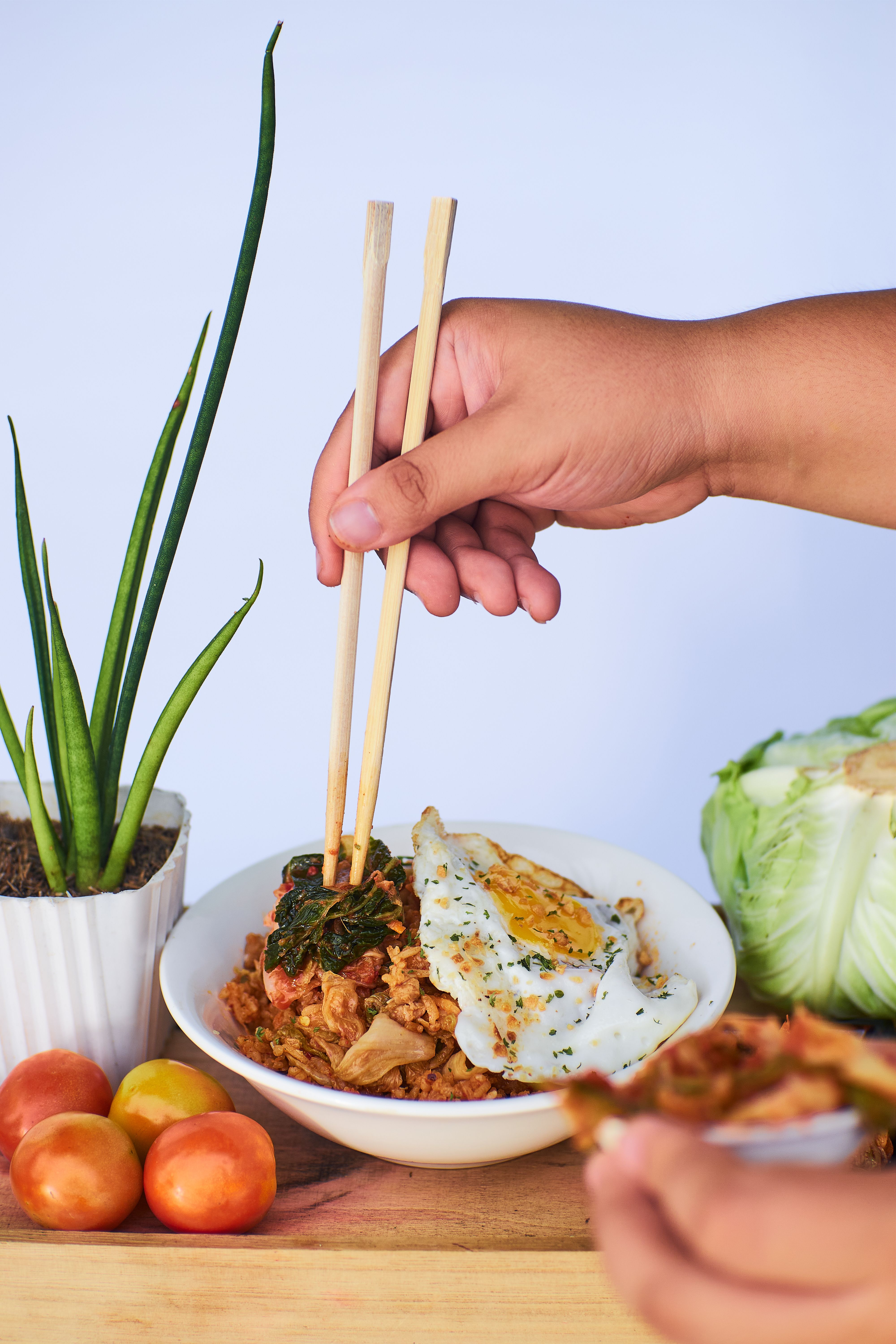Appetizing food with chopsticks, fried egg, and vegetables on a wooden table.